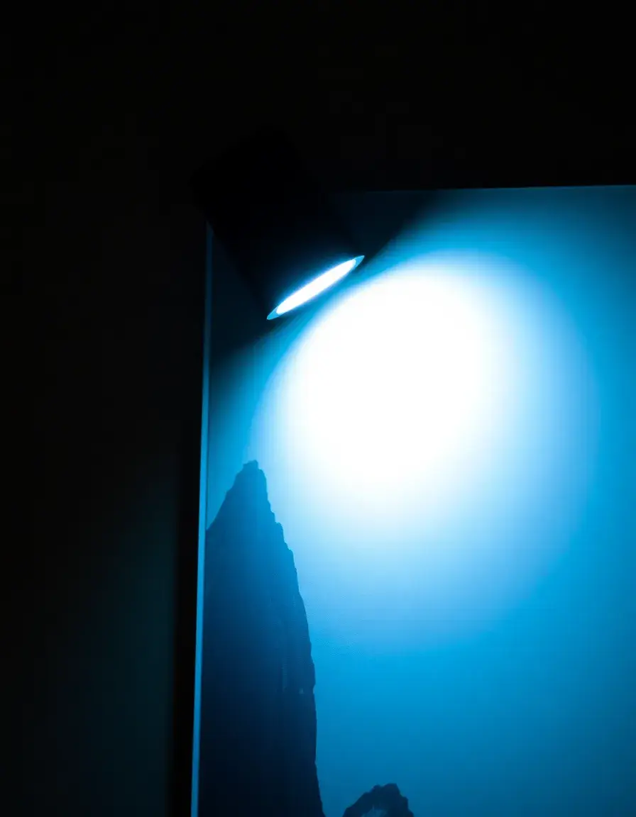 Petite lampe LED à pince éclairant une affiche murale